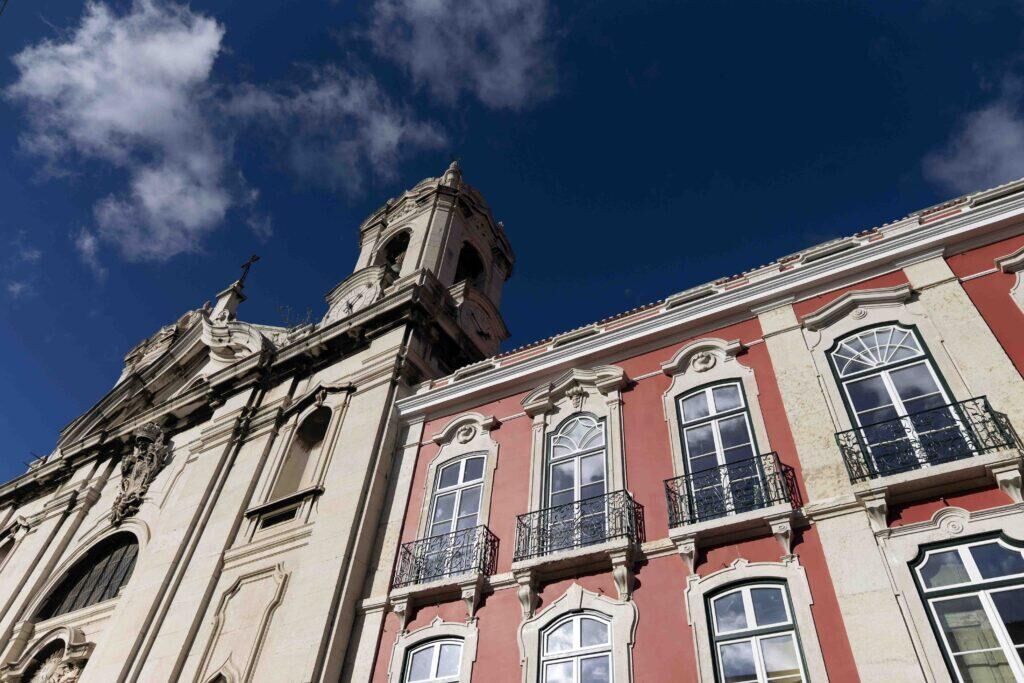 bright lisbon buildings painted pastel pink with blue sky above them