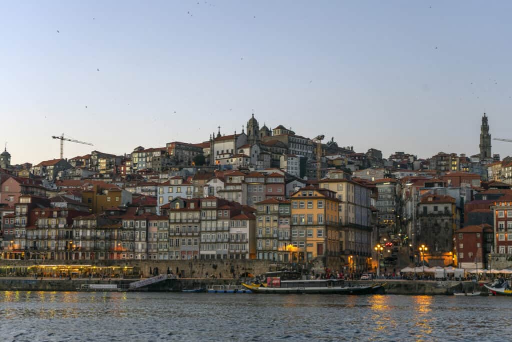 view of buildings lit up along a river at sunset in Porto, portugal